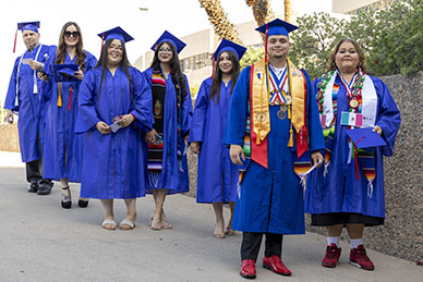 A group of seven graduates standing outside the arena