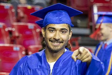 A graduate points to the camera in the arena
