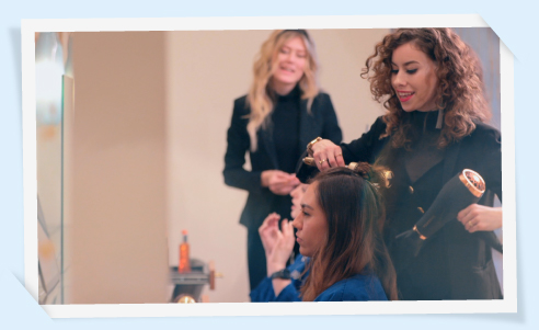 A stylist drying a client's hair with a hairdryer.