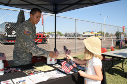 9/11 Commemoration event, soldier handing flag to little girl