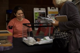 A woman standing behind a glass tank with a critter inside