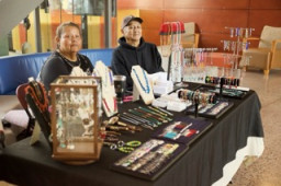 Vendors sitting at a table with jewelry displayed