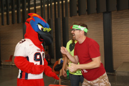 Thor wearing sunglasses standing with student in red shirt and green headband