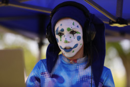 Person with face painted and wearing a hat.