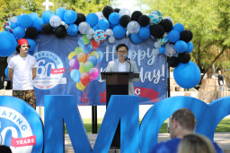Two students standing on stage behind podium at birthday celebration