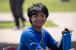 Student wearing blue shirt holding water bottle while sitting down