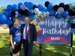 Marcy Snitzer and Dr. Daniel standing in front of happy birthday sign