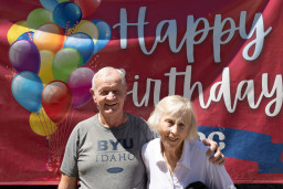 Man and woman standing in front of happy birthday sign.