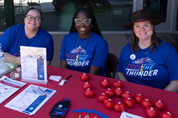 3 women sitting at booth with information about MCC
