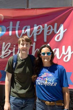 Two people standing in front of Happy Birthday sign.