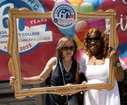 Two women holding up a photo frame posing for a picture