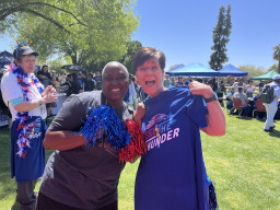 Two MCC employees holding pom poms and Feel the Thunder shirt