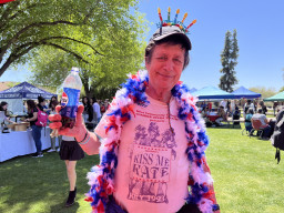 Man wearing a feather boa and holding a soda bottle at celebration.