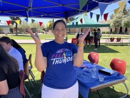 Meena Patel standing with arms raised under a tent.