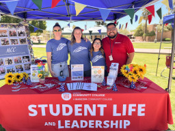 Employees standing behind table at Student Life and Leadership table at celebration