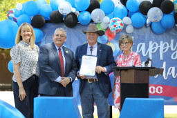 City of Mesa employees with MCC president on stage holding proclamation.