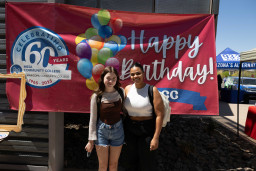 Two women standing in front of happy birthday sign at Red Mountain campus.