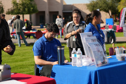 Man in blue shirt sitting at a table with Trio information, woman in blue shirt standing nearby