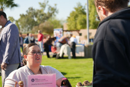 Unidentified male asking a woman wearing glasses a question at the information table for Disability Resource Services
