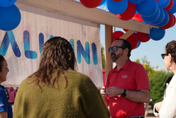 Four people standing in front of Alumni information table