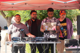 Four students at DJ booth with equipment