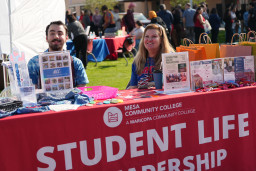 Man and woman sitting at Student Life and Leadership information table
