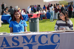 Two students sitting at ASMCC information table