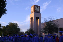 Line of students marching to graduation ceremony by MCC's Clock Tower