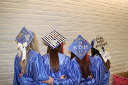 4 students showing their dental hygiene decorations on their mortarboards
