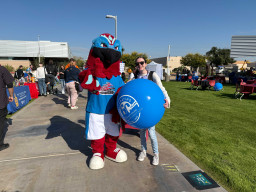 Thor standing with a student holding a large blue balloon.