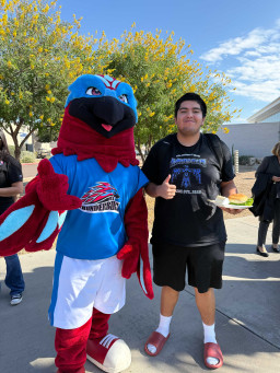 Thor posing with a student wearing a black shirt, black shorts and holding a plate of food.