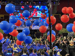 Red and blue balloons falling from ceiling over graduating students