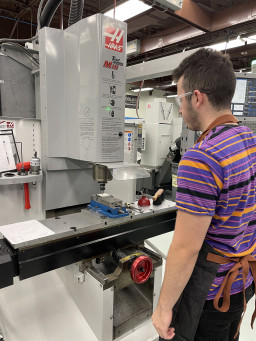 Student standing in front of machine in lab