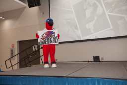 Thor holding a "Go Thunderbirds" sign on a stage