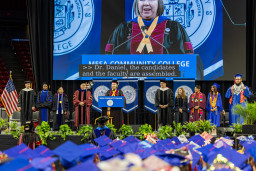 Dr. Pam Harrison at lectern with MCC platform party members in the background