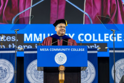 Dr. Richard Daniel speaking at podium in his cap and gown