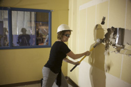 Dawn Rhodes using a sledgehammer to break a wall in the Kirk Center