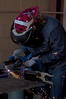 Student in protective helmet and mask welding metal