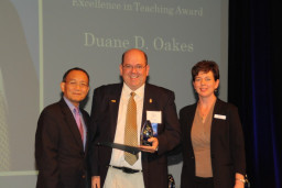 Inductee Duane Oakes is joined on stage by MCC President Dr. Shouan Pan and Marcy Snitzer, Alumni Relations Coordinator.