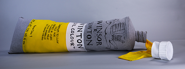 Soft sculpture of a yellow paint tube.