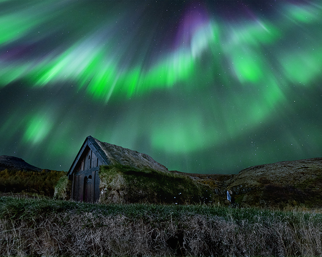 Photograph of an aurora above a barn in Iceland.