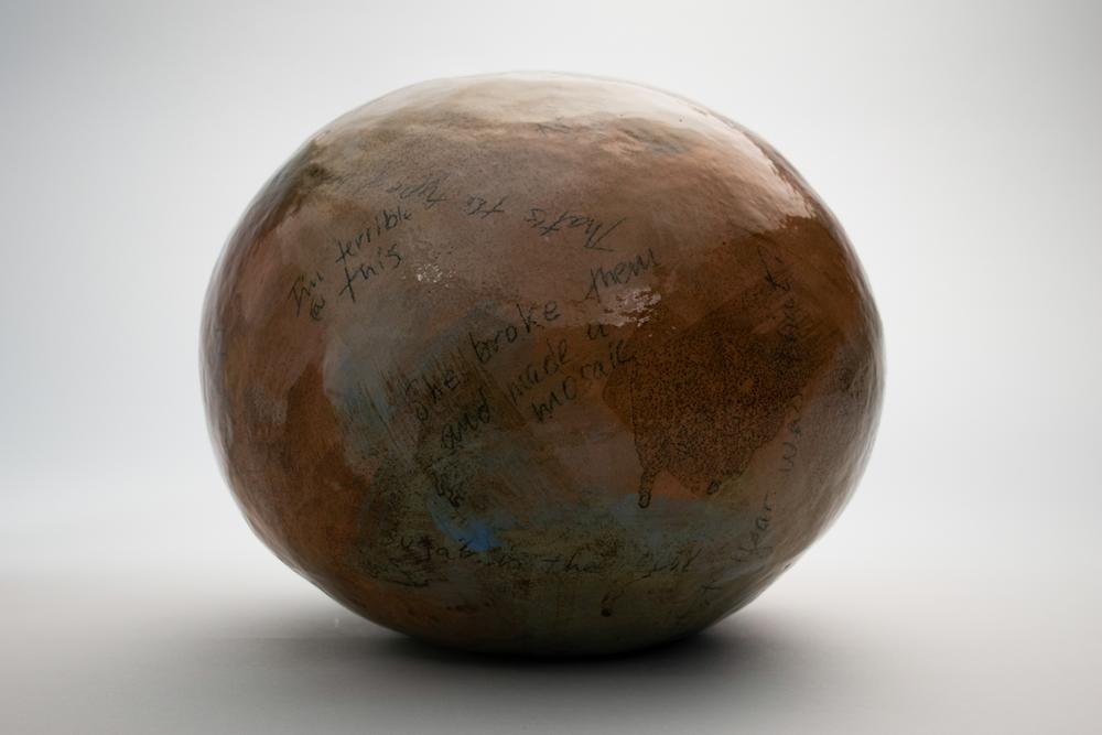 Ceramic spherical sculpture with words written on it.