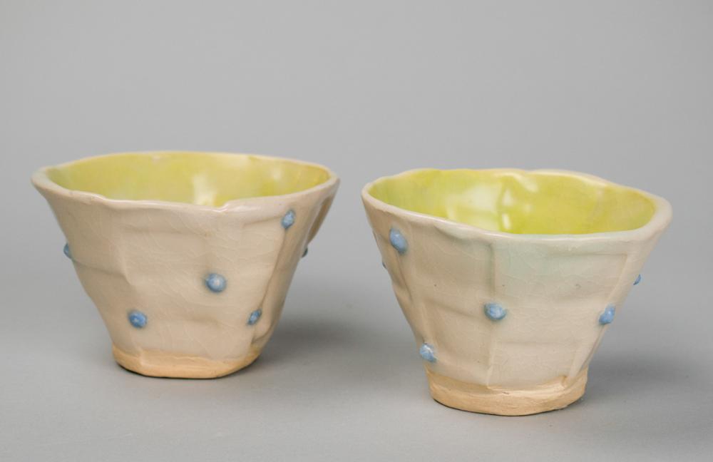 Two dishes with dots on the exterior, and a yellow glaze on the interior.