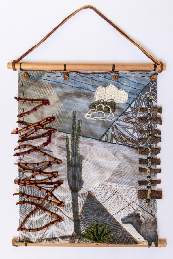 Textile work with a cactus in a landscape and added found objects in relief.