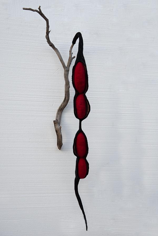 Oversized textiles sculpture of a seedpod hanging from a branch.