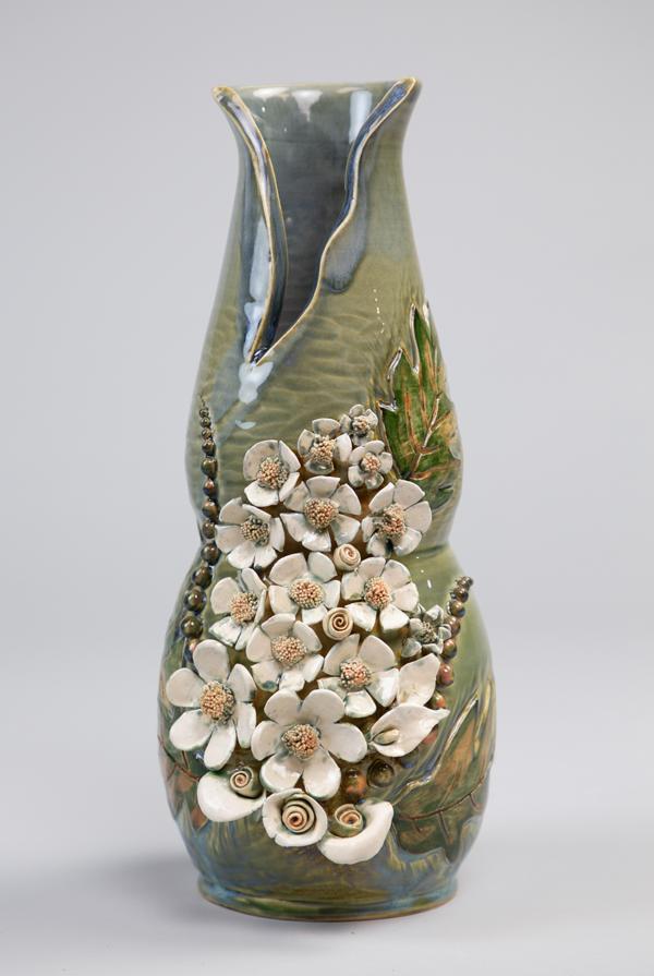 Green ceramic vase with white flowers.