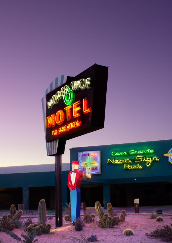 Photograph of neon signs in front of a purple sky.