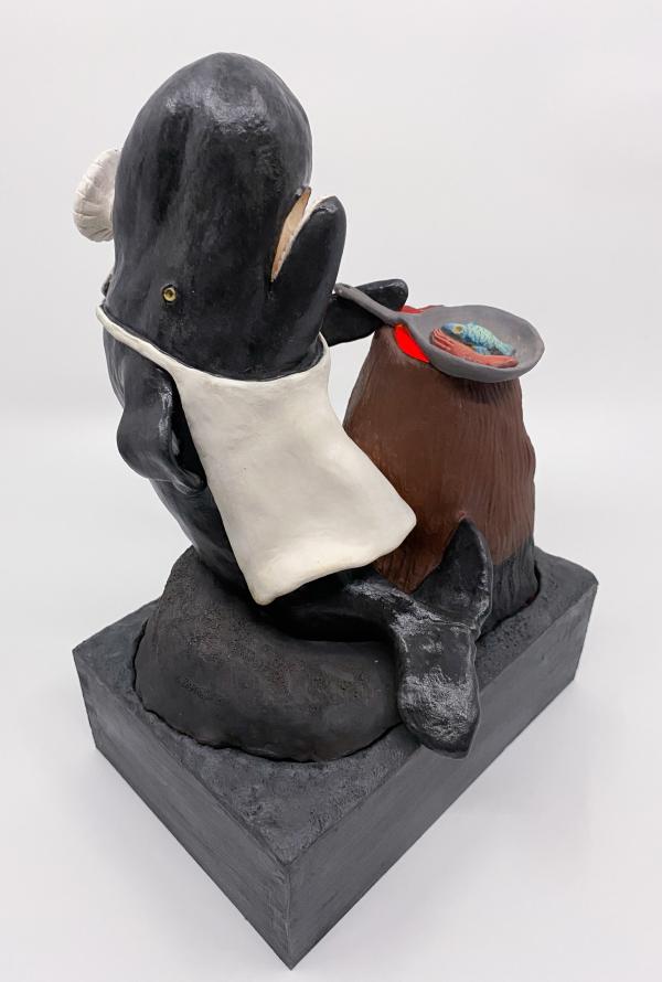 Ceramic sculpture of a whale with a chef hat and a frying pan.