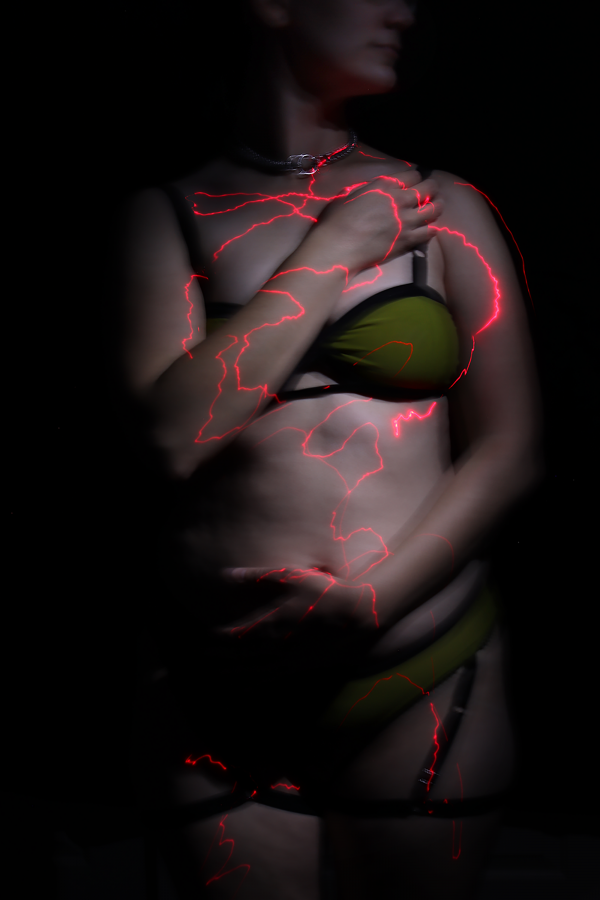 Photograph of a female figure with red lighting reflected on their body.