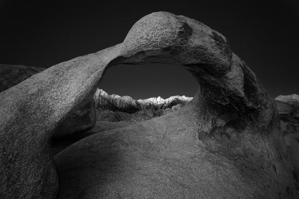 Digital photograph of an arched rock in a landscape.